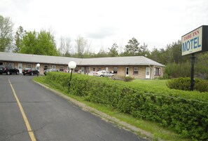A motel with a brick exterior, multiple rooms, and a parking lot.