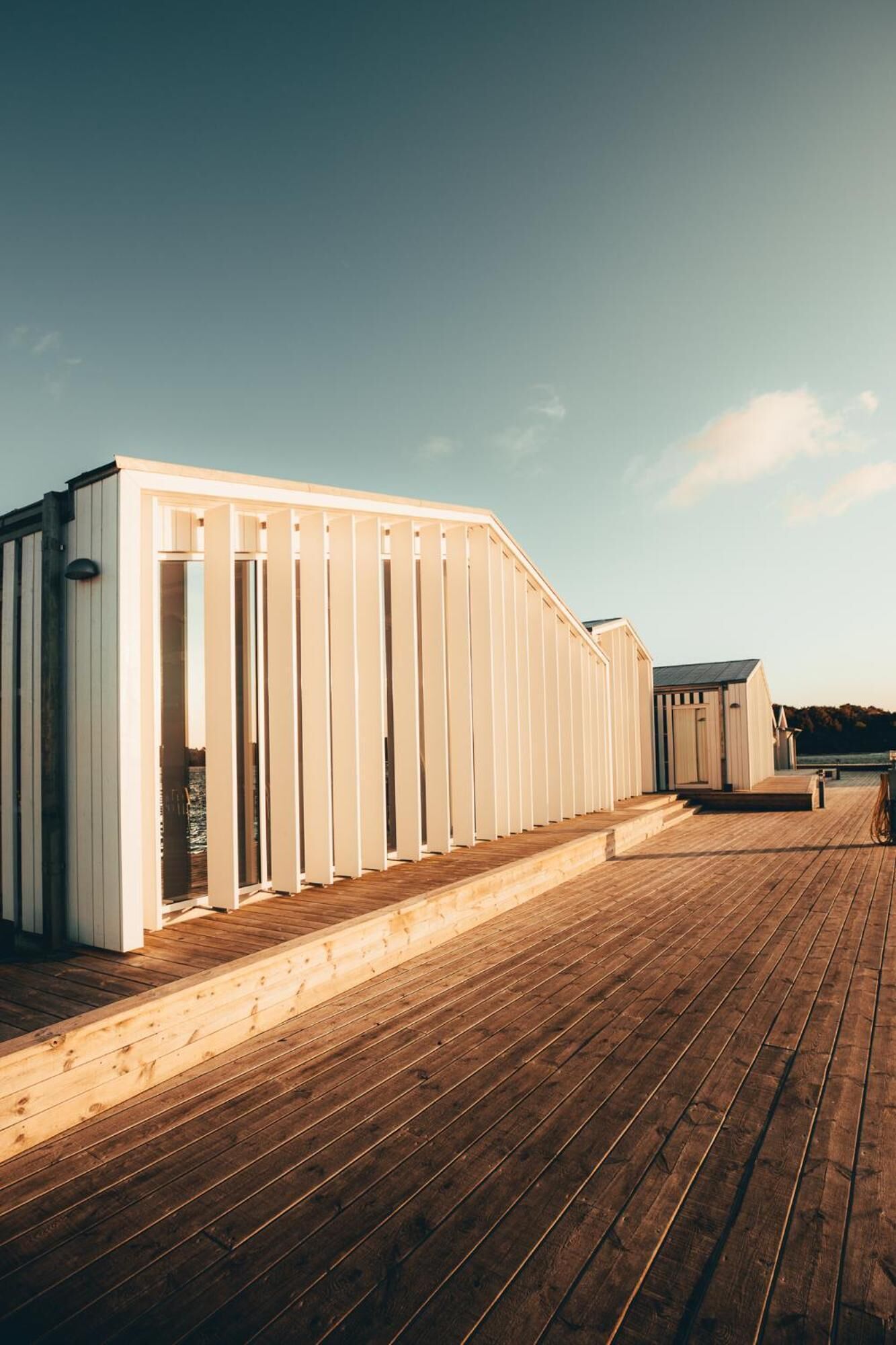 Una terraza de madera con una hilera de edificios blancos, probablemente parte de un complejo turístico o hotel.