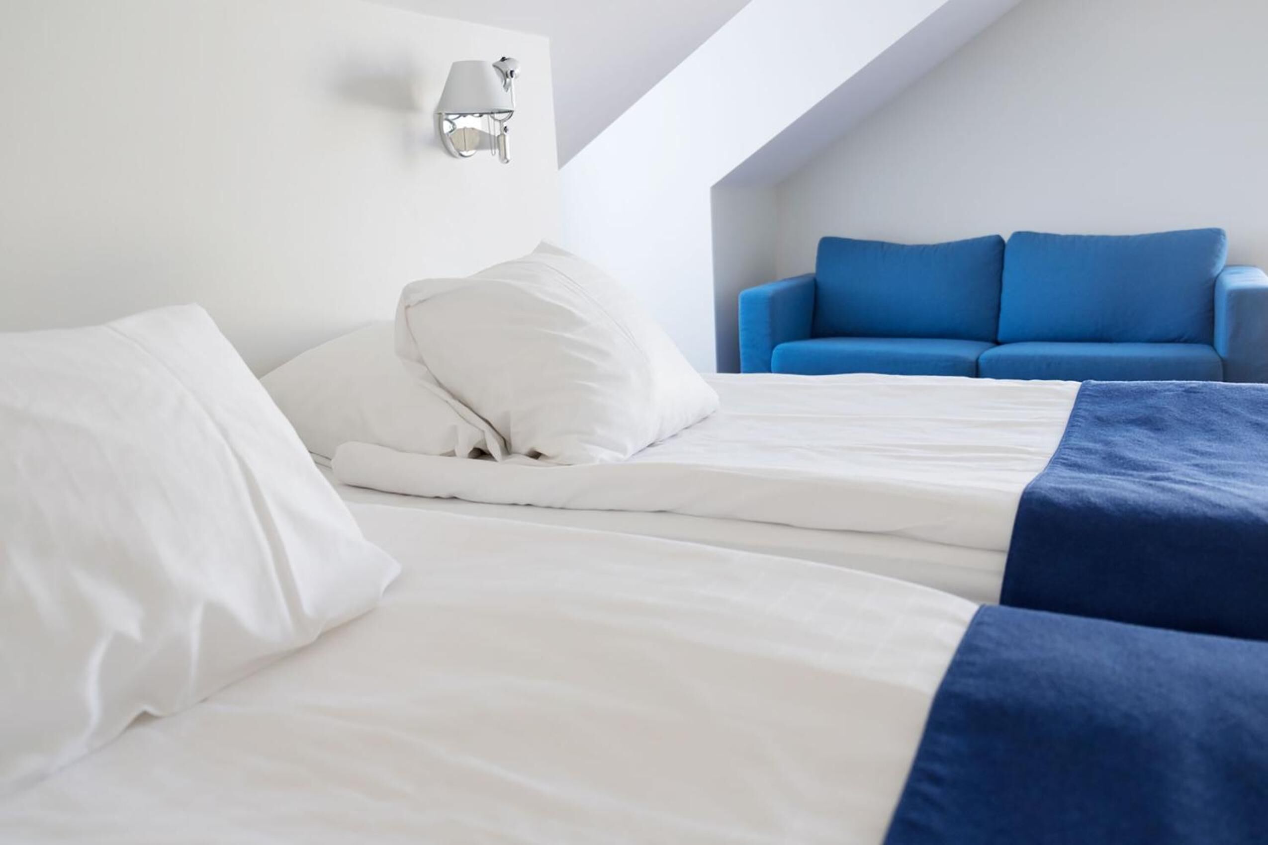 A neatly made bed with white bedding and a blue accent.