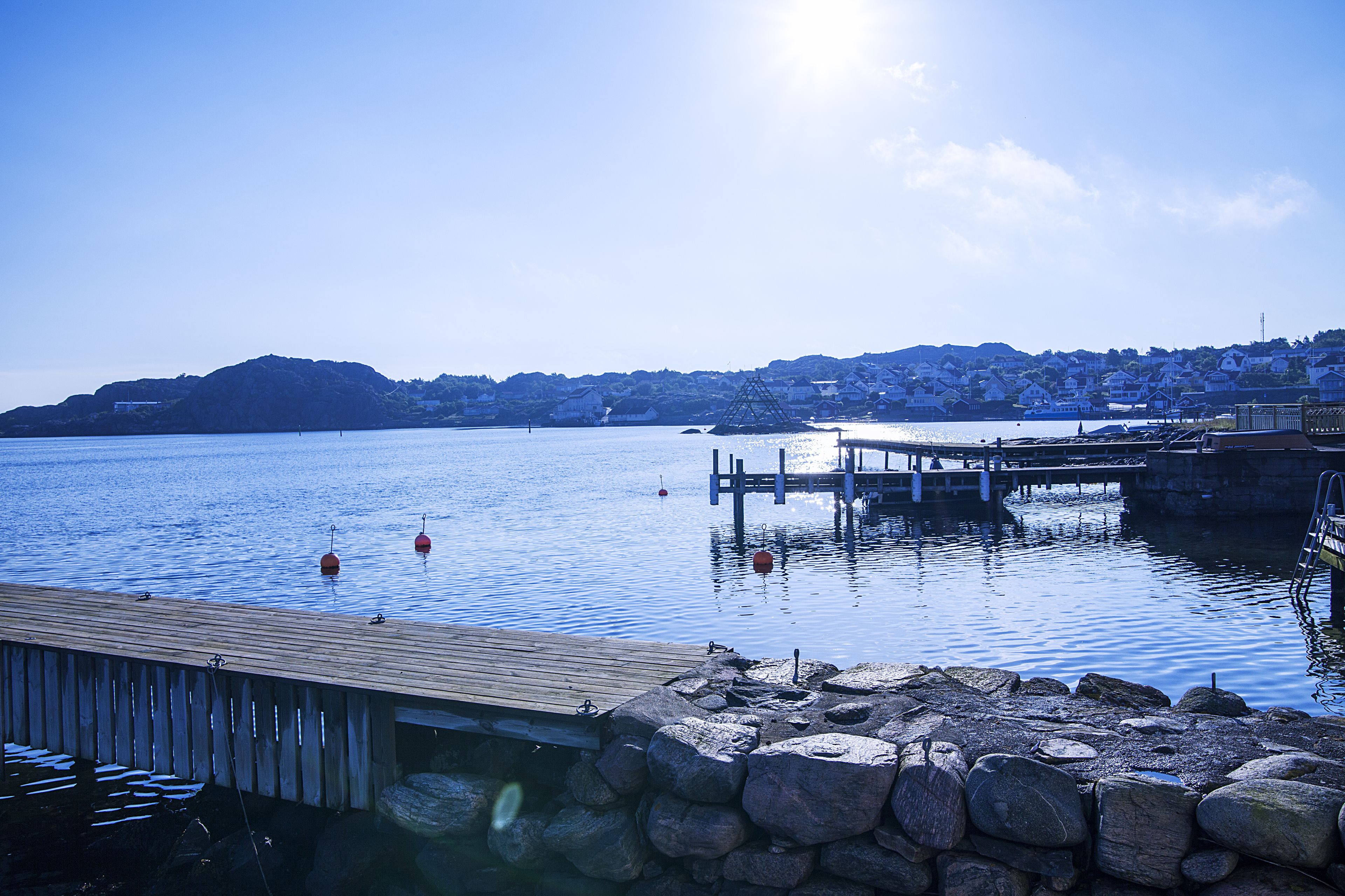 Un lago tranquilo con un muelle de madera que se adentra en el agua, rodeado por un muro de piedra.