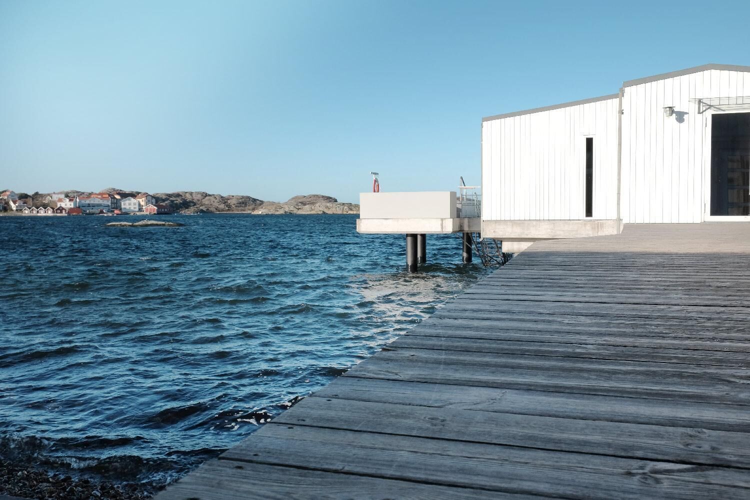 A wooden pier extending into a body of water with a white building at the end.