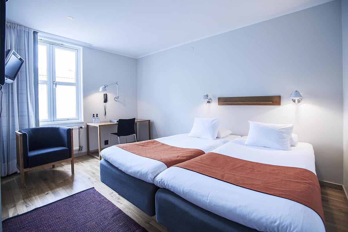 Ein Hotelzimmer mit zwei Betten, einem Schreibtisch, einem Stuhl und einem Fernseher.
