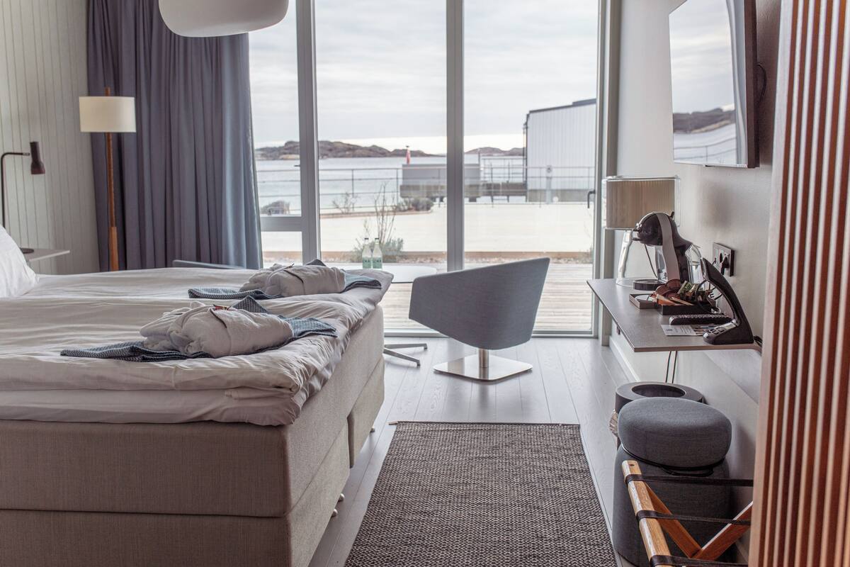 Ein modernes Hotelzimmer mit einem großen Bett, einem Schreibtisch und Meerblick.