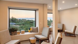 Una sala de estar moderna con un amplio ventanal que ofrece vistas a un paisaje pintoresco, con varias opciones de asientos cómodos y una pequeña mesita.