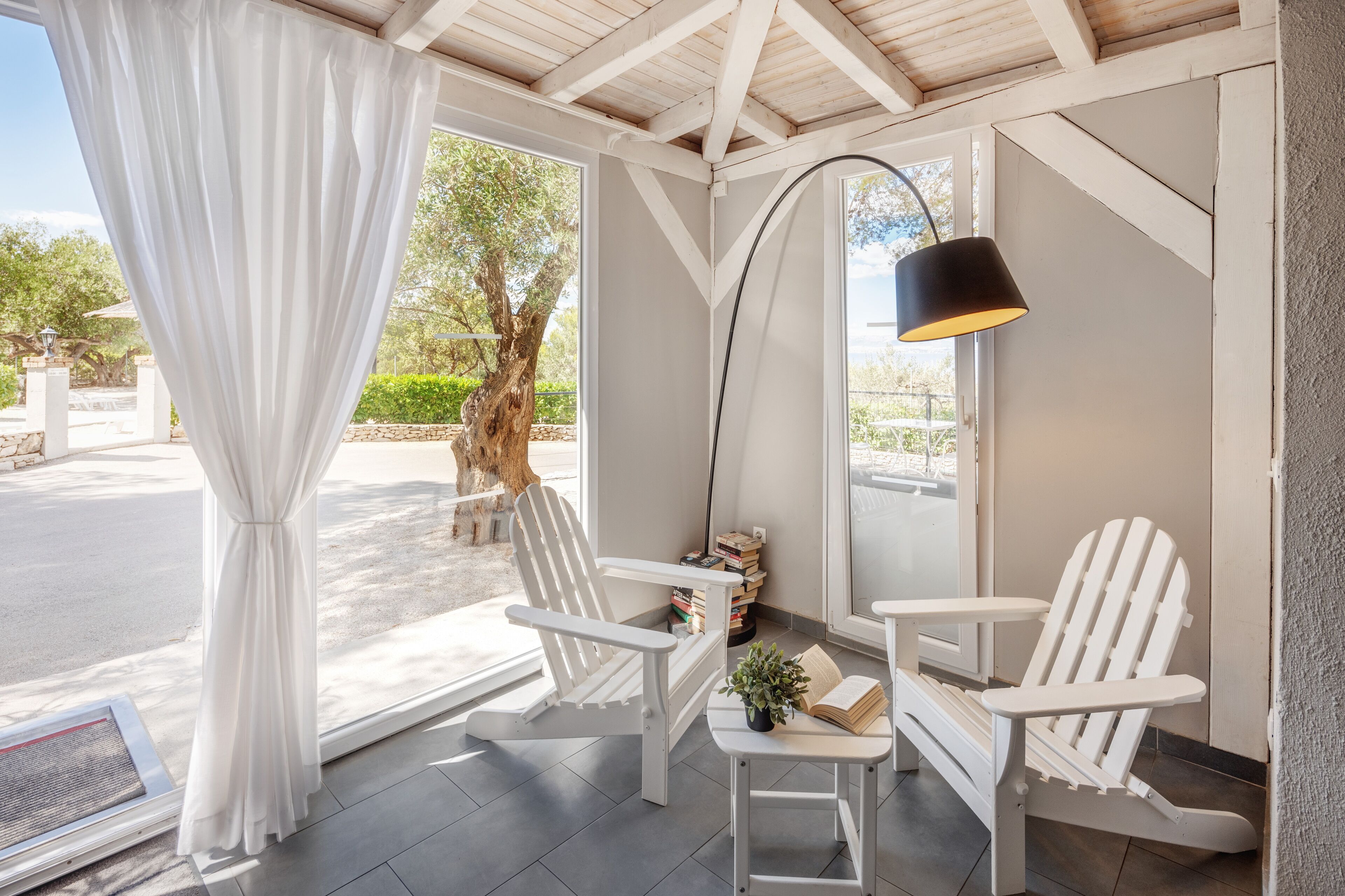 A cozy reading nook with white chairs, a small table, and a lamp.