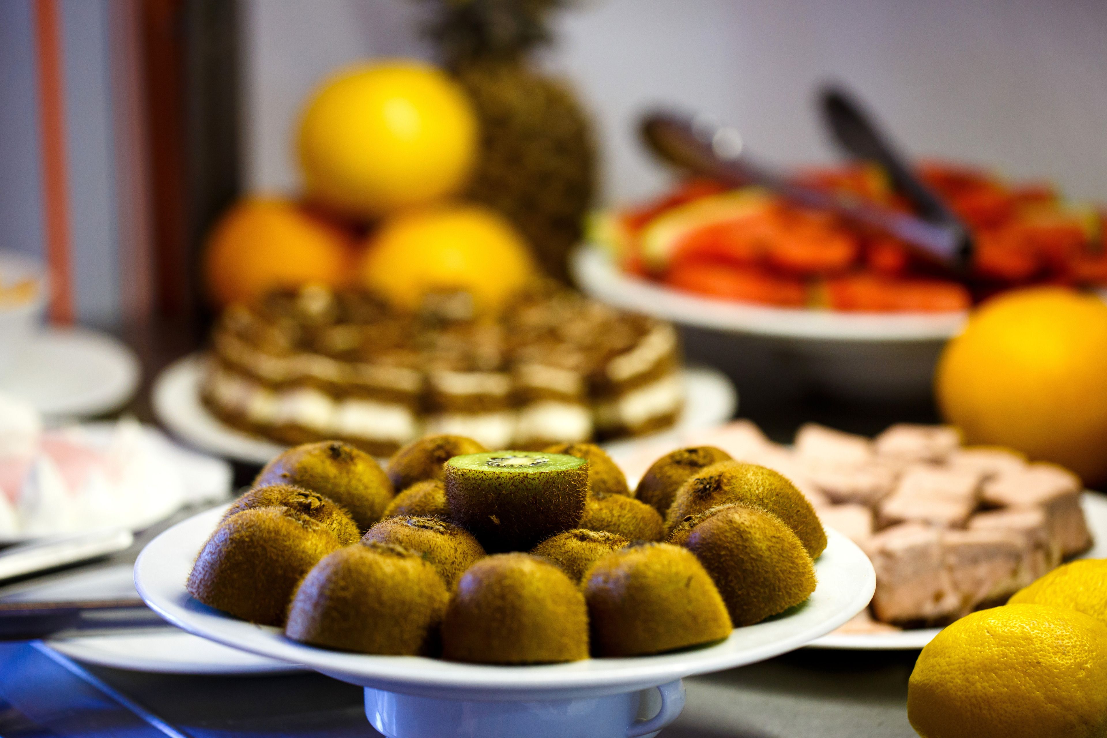 A buffet with various dishes including a plate of round, golden-brown items, a slice of cake, and a plate of sliced meat.