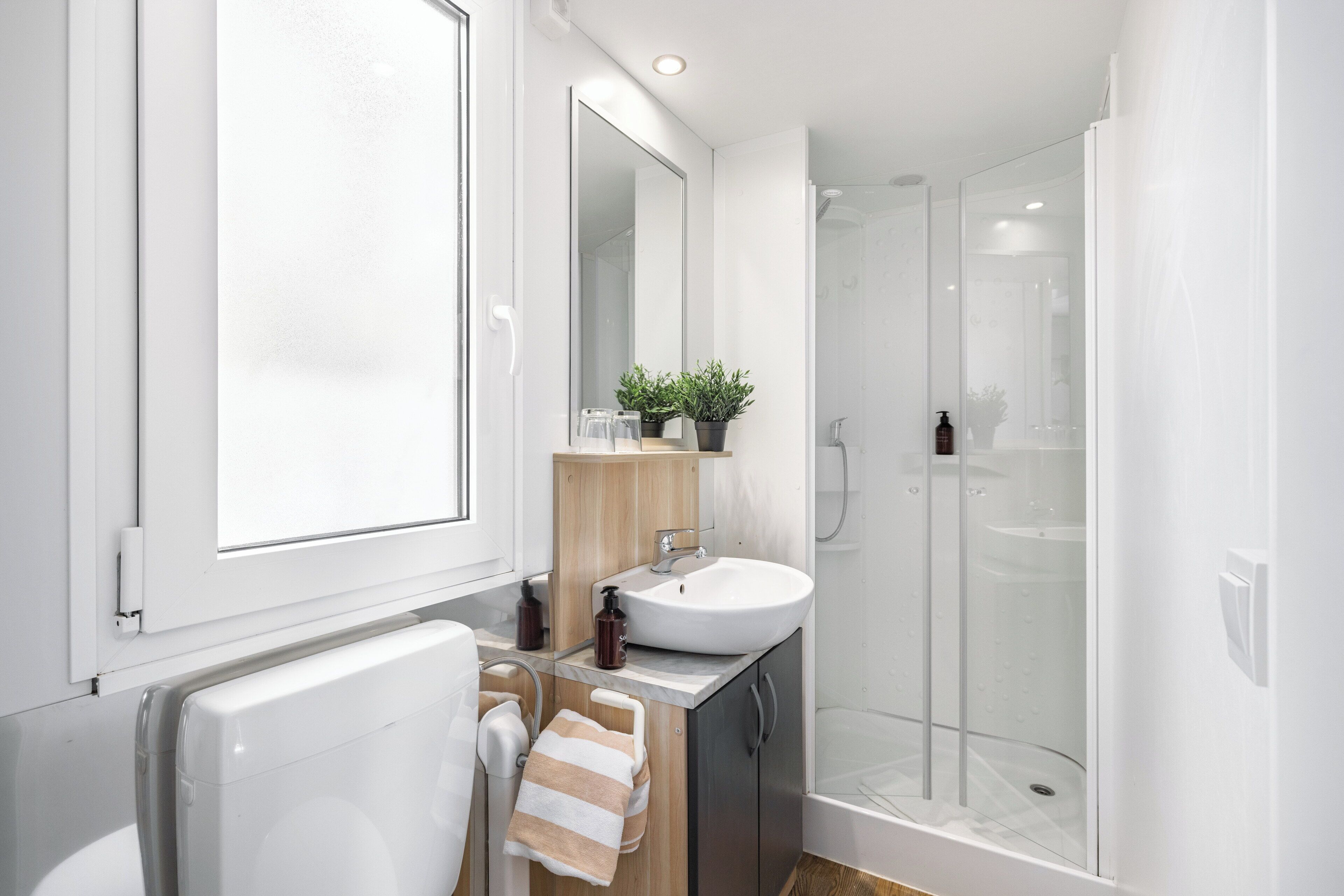 A modern bathroom with a large mirror, a sink, a shower, and a towel rack.