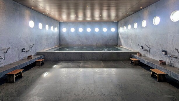 A modern spa with a large central hot tub, benches along the walls, and circular lights on the ceiling. - Zuri Express Lippo Cikarang (Bekasi)