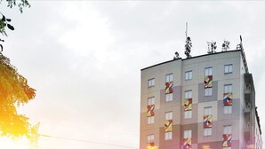 A modern hotel building with multiple floors, large windows, and a prominent red section. - Zuri Express Lippo Cikarang (Bekasi)