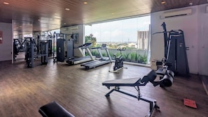 A modern gym with various exercise equipment, large windows, and a wooden ceiling. - Zuri Express Lippo Cikarang (Bekasi)