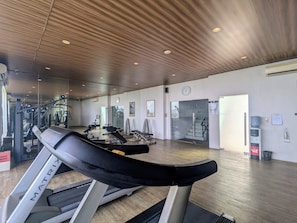 A gym with treadmills, weight machines, and a mirrored wall.