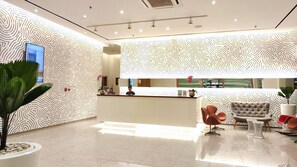 A modern reception area with a patterned wall, a reception desk, and seating.