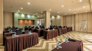 A conference room with multiple tables, each with a brown tablecloth, water bottles, and glasses. There is a whiteboard on a stand in the room.
