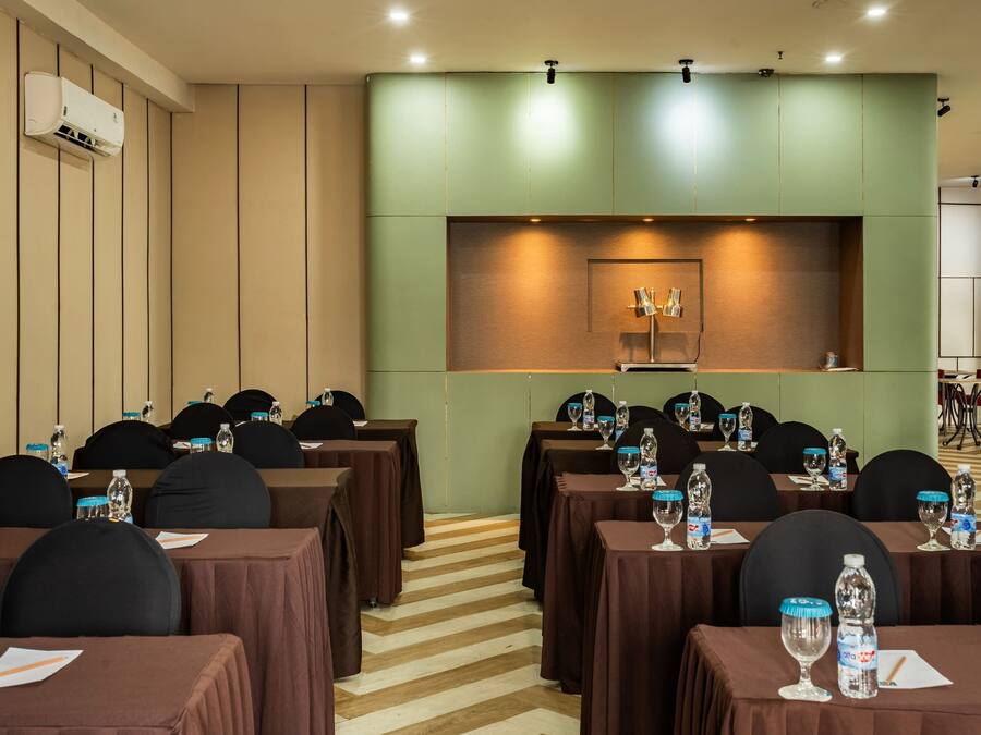 Un salón de conferencias con mesas, sillas y botellas de agua.