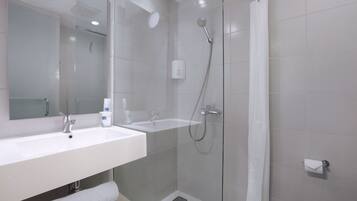 Un baño moderno con ducha envuelta en vidrio, un lavamanos blanco y un inodoro.