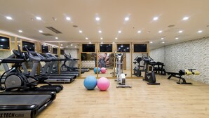 Un gimnasio con cintas de correr, bicicletas estáticas y pelotas de ejercicio.