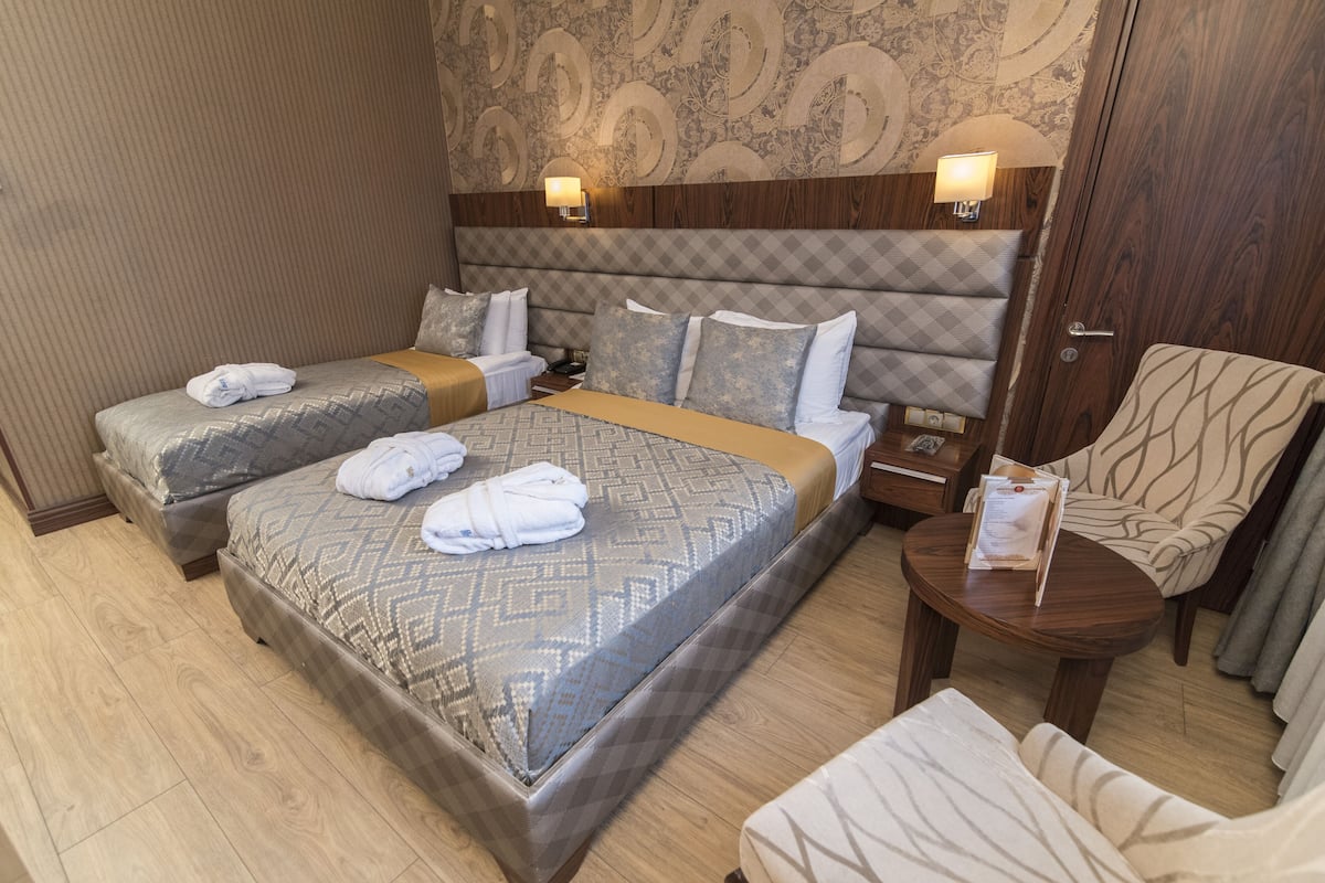 A hotel room with two beds, a wooden headboard, a small round table, and a chair.