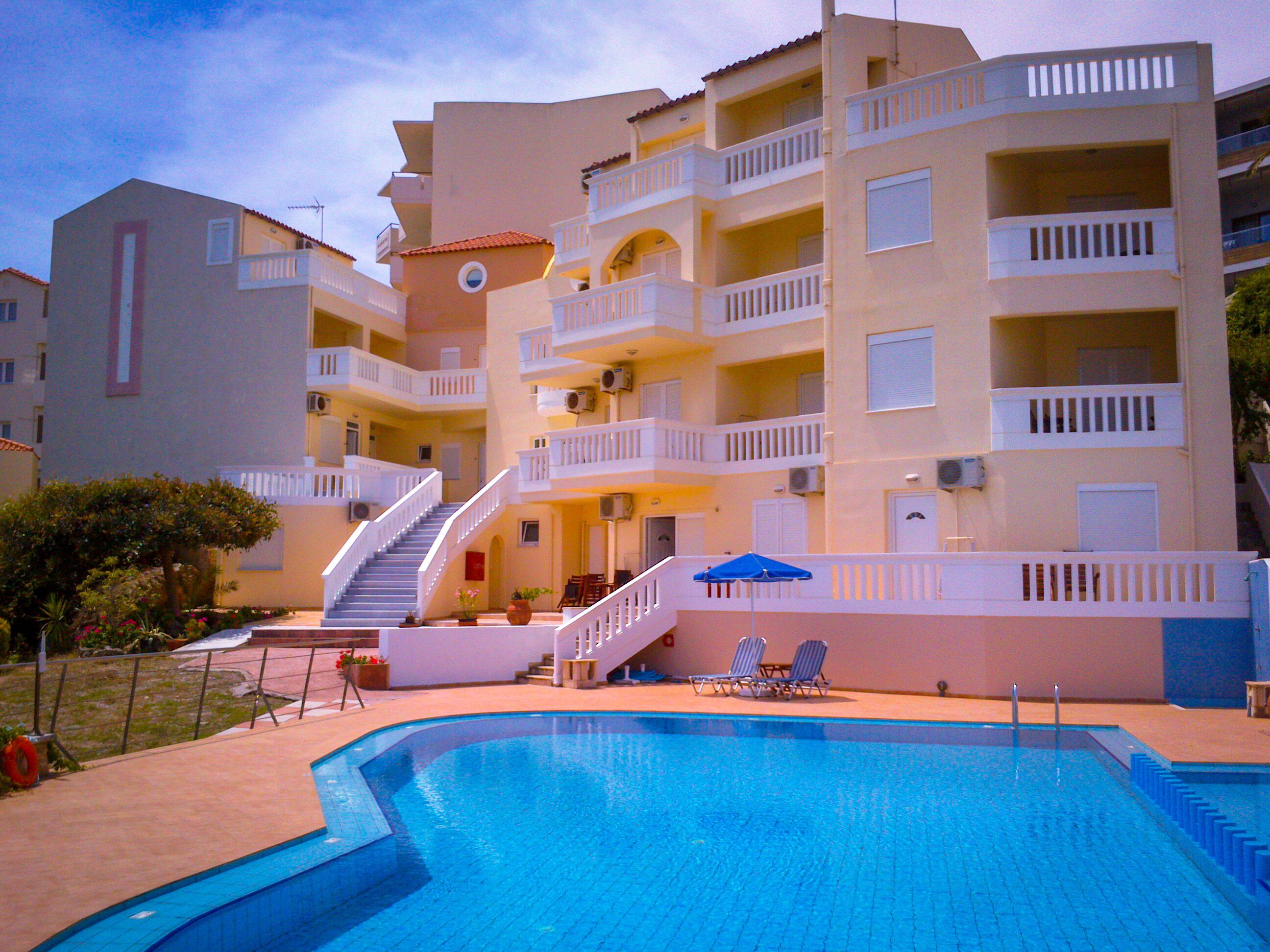 A hotel with a swimming pool, multiple balconies, and a staircase leading to the upper floors.