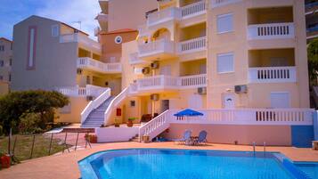 A hotel with a swimming pool, multiple balconies, and a staircase leading to the upper floors.