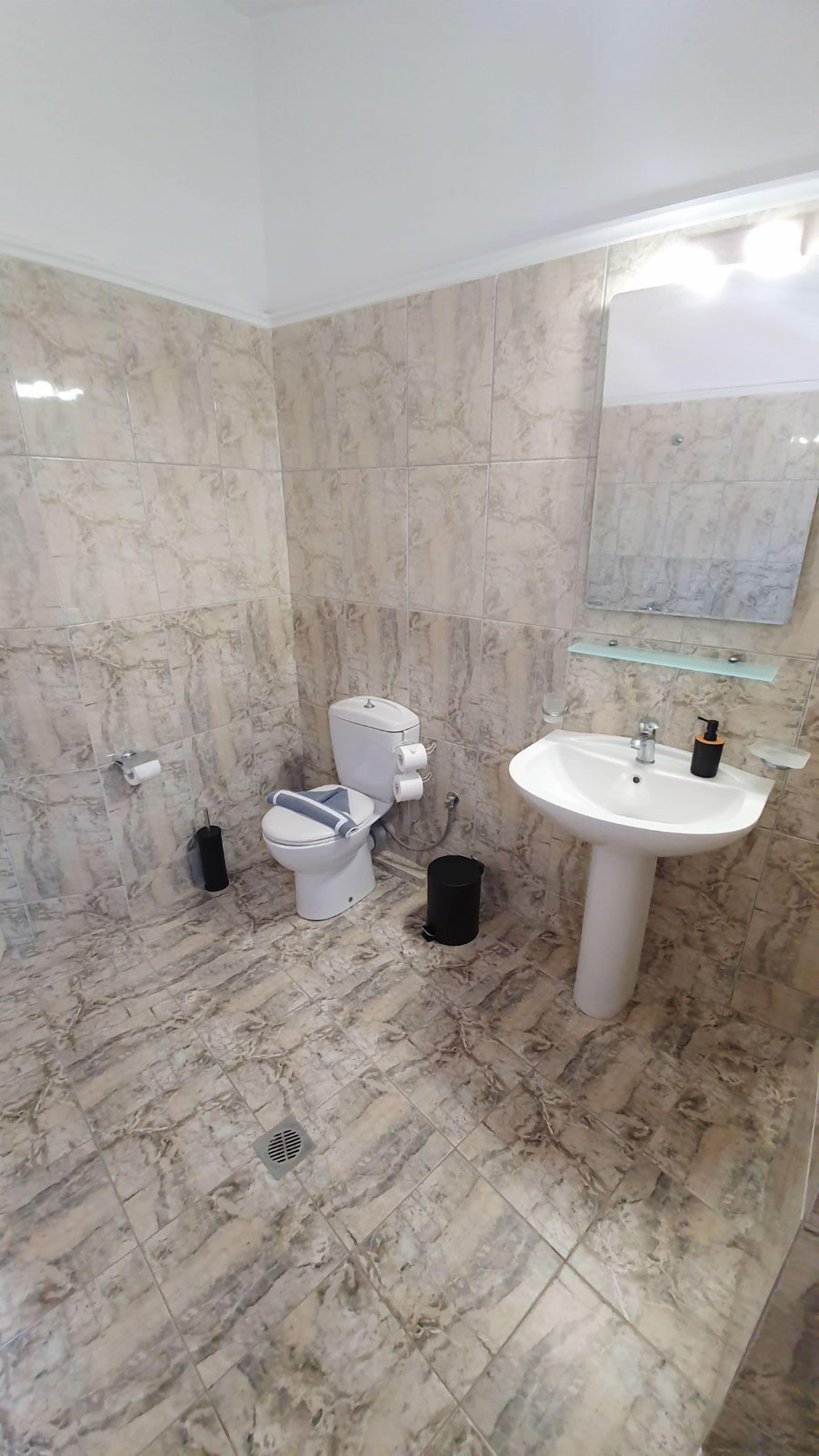 Une salle de bain avec un sol en marbre, un lavabo blanc et des toilettes.