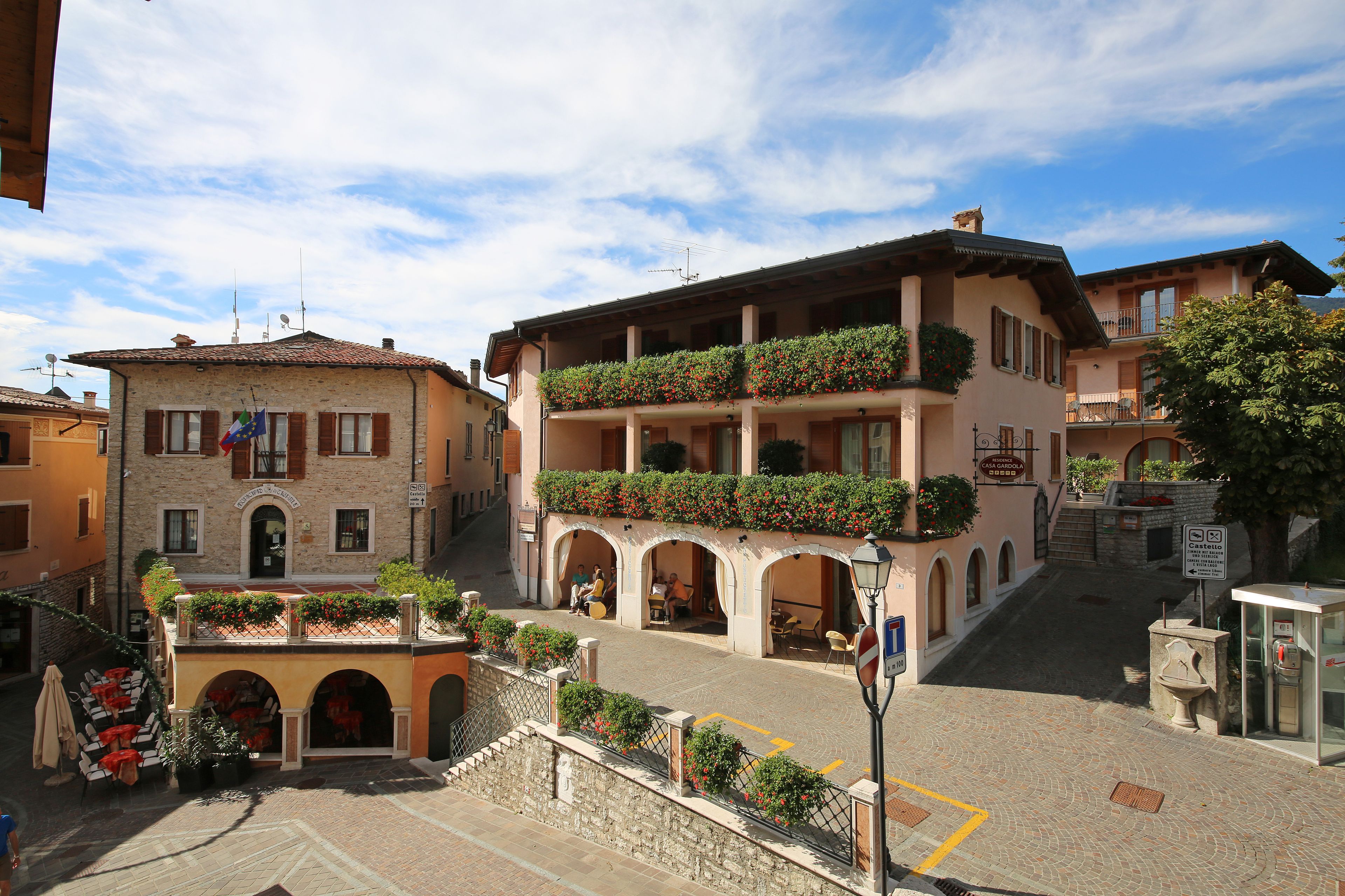 A traditional European building with a ground floor café and upper-level balconies with flower boxes.