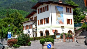 A multi-story building with a white facade and brown shutters, featuring a large mural on the side. - Residence Casa Gardola (Tignale)