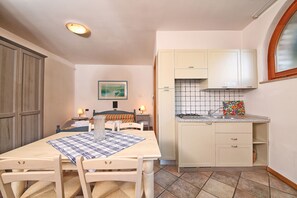 A small kitchen with a dining table, chairs, and a tiled backsplash. - Residence Casa Gardola (Tignale)
