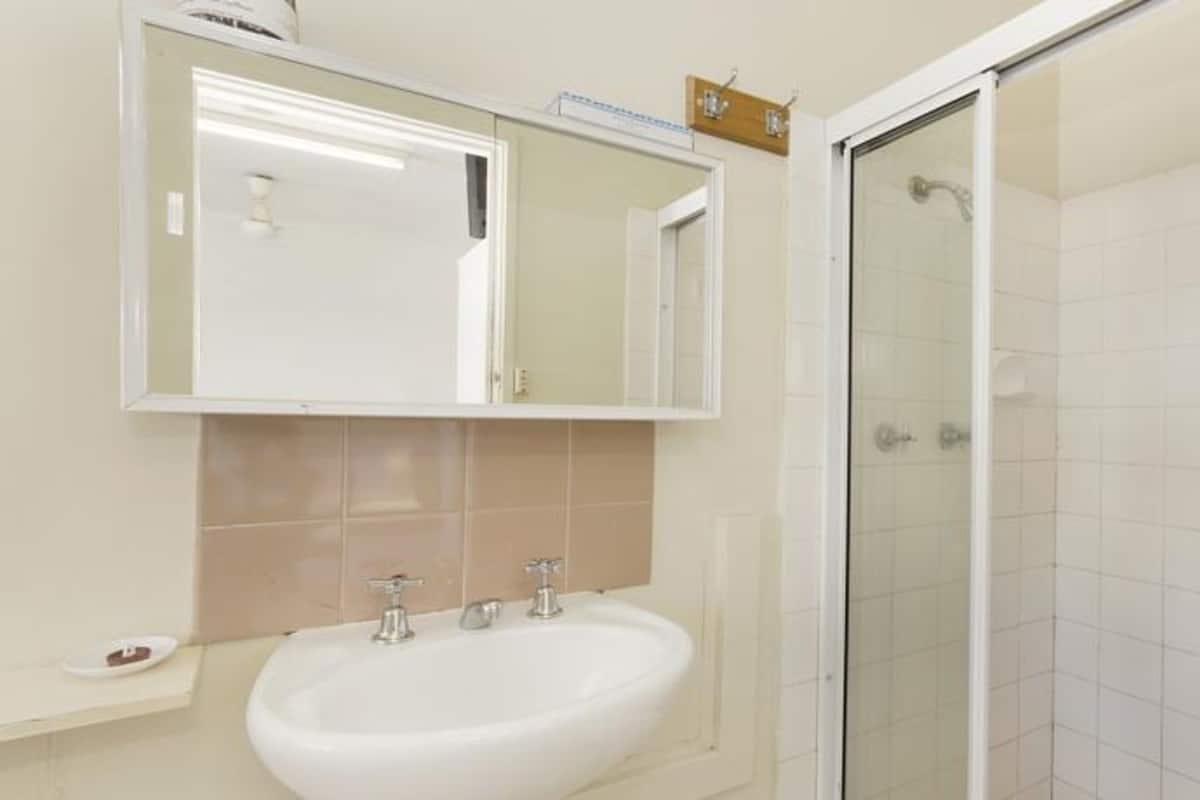 Une salle de bain avec un lavabo blanc, un miroir et une cabine de douche en verre.