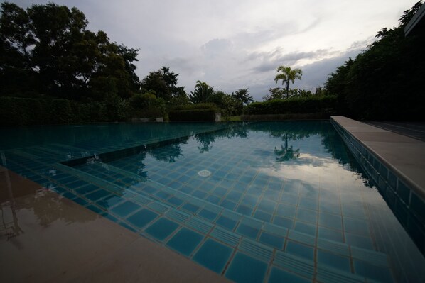 Una piscina al aire libre, sombrillas, sillones reclinables de piscina