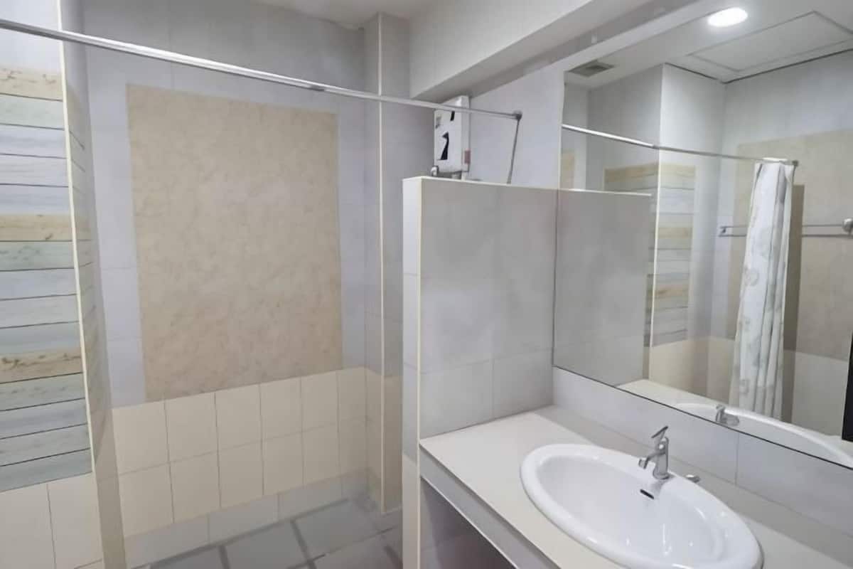 Un baño con cabina de ducha de vidrio, un lavamanos blanco y un espejo grande.