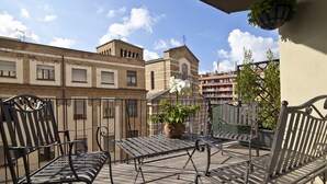 A balcony with metal furniture, a potted plant, and a view of buildings.