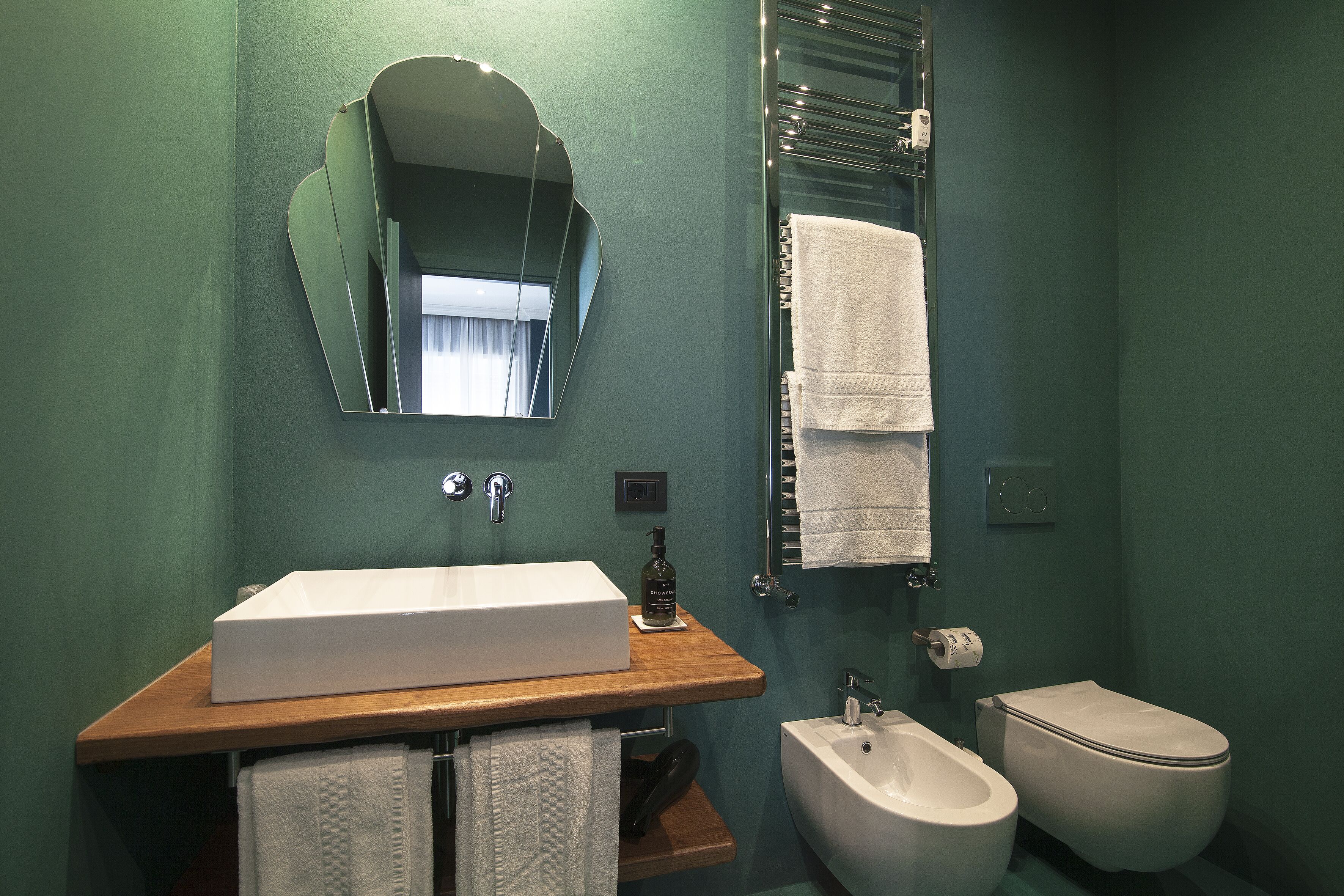 A bathroom with a white sink, a mirror, a bidet, and a towel rack.