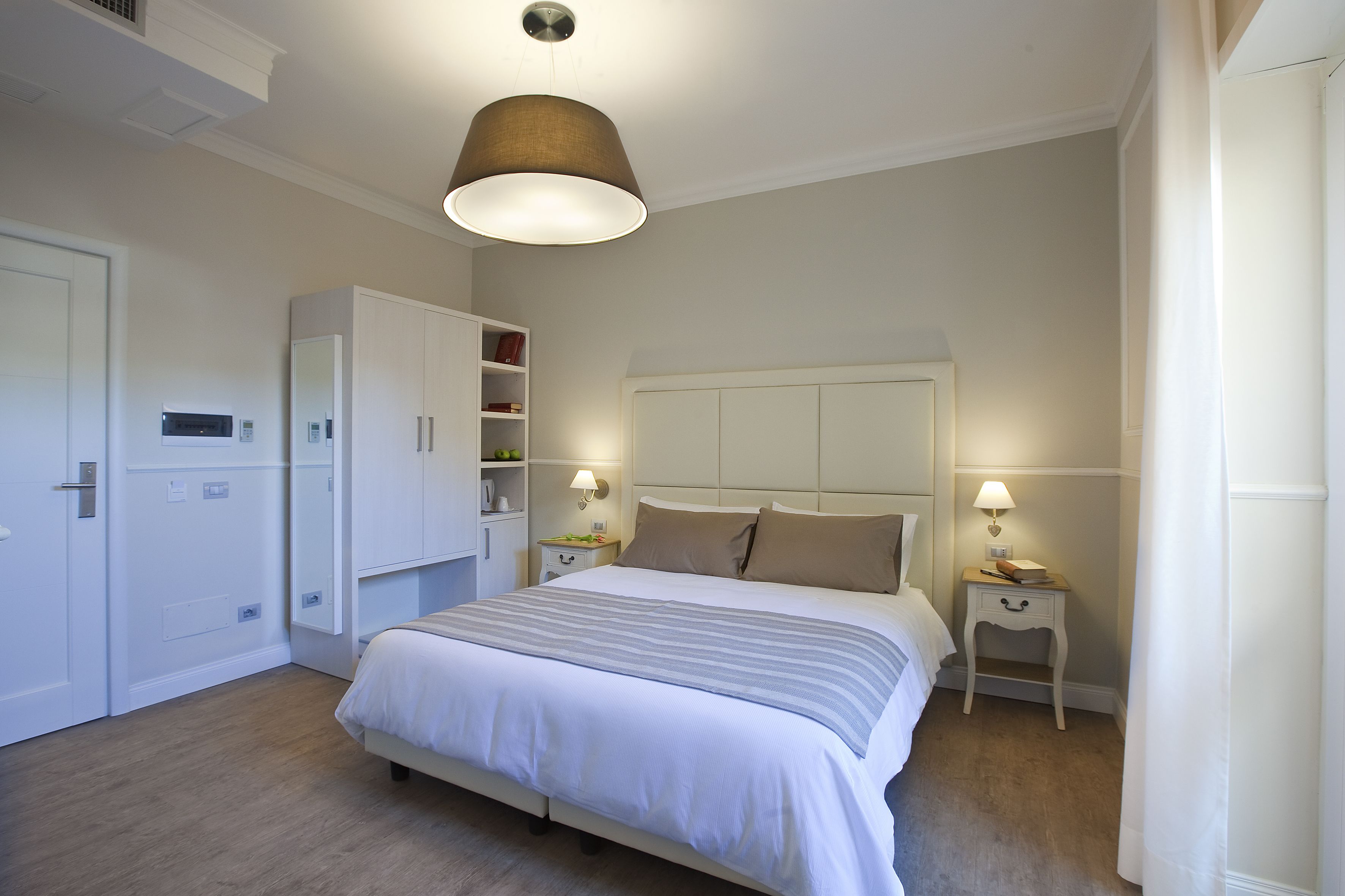 A bedroom with a bed, bedside tables, a wardrobe, and a hanging light fixture.