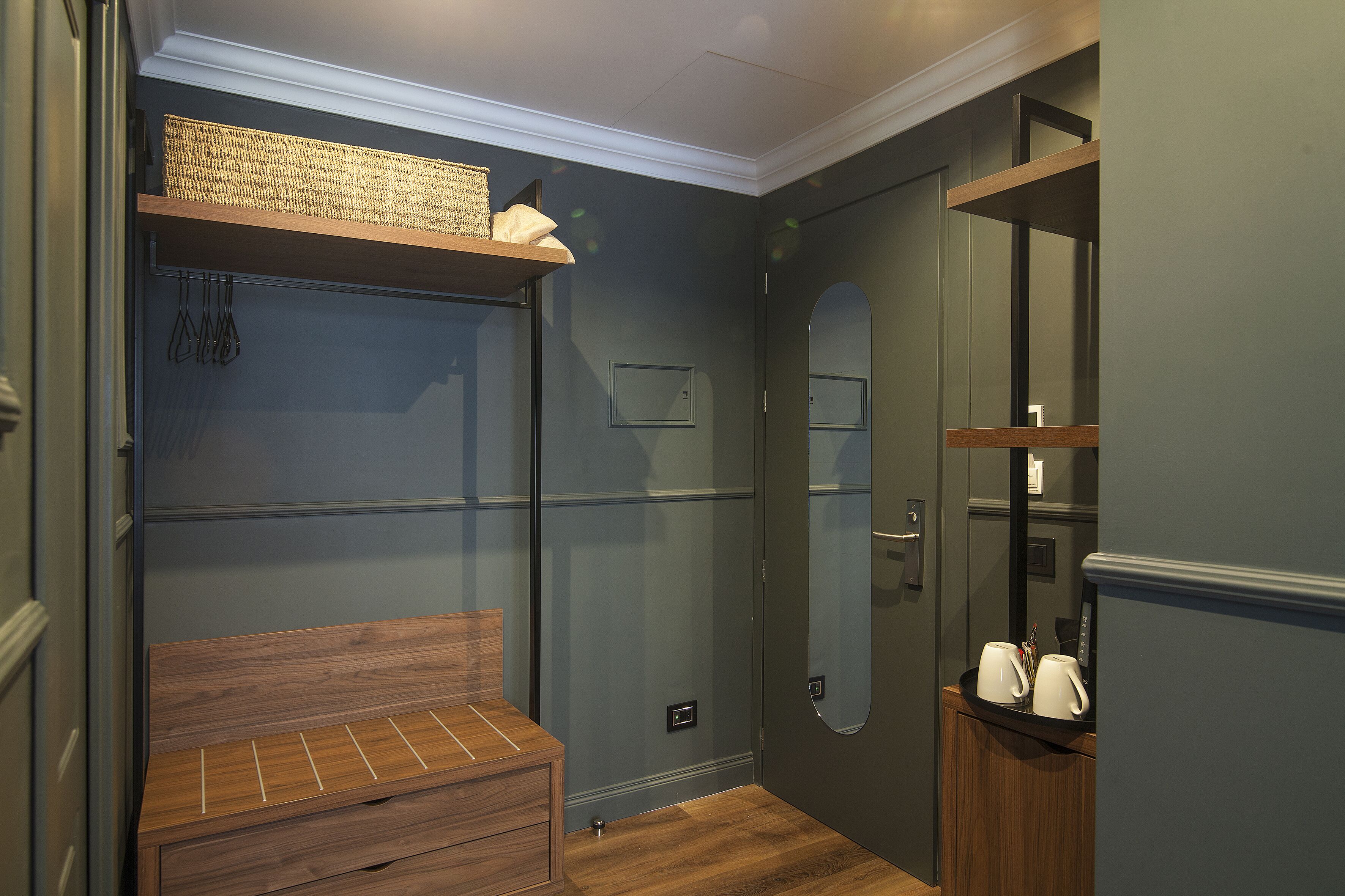 A compact room with a built-in bench, a small shelf, and a mirror.