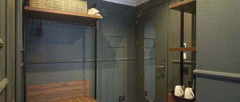 A compact room with a built-in bench, a small shelf, and a mirror.