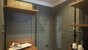 A modern bathroom with a wooden vanity, an ironing board, and a coffee maker.