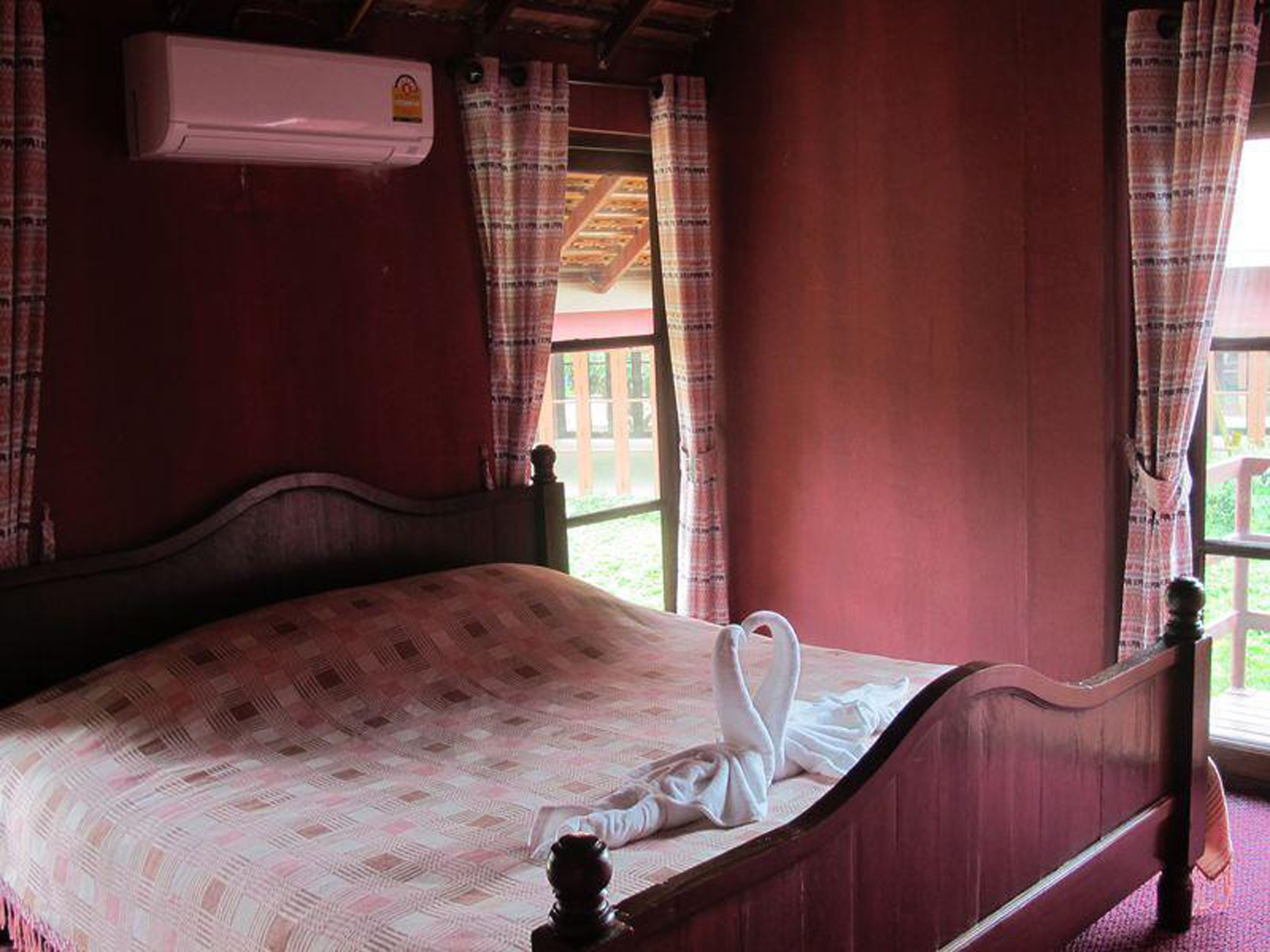 A bed with a patterned bedspread, a wooden headboard, and a white towel on the bed.