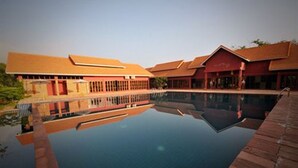 Un hotel con piscina, edificios de techo rojo y cielo despejado.