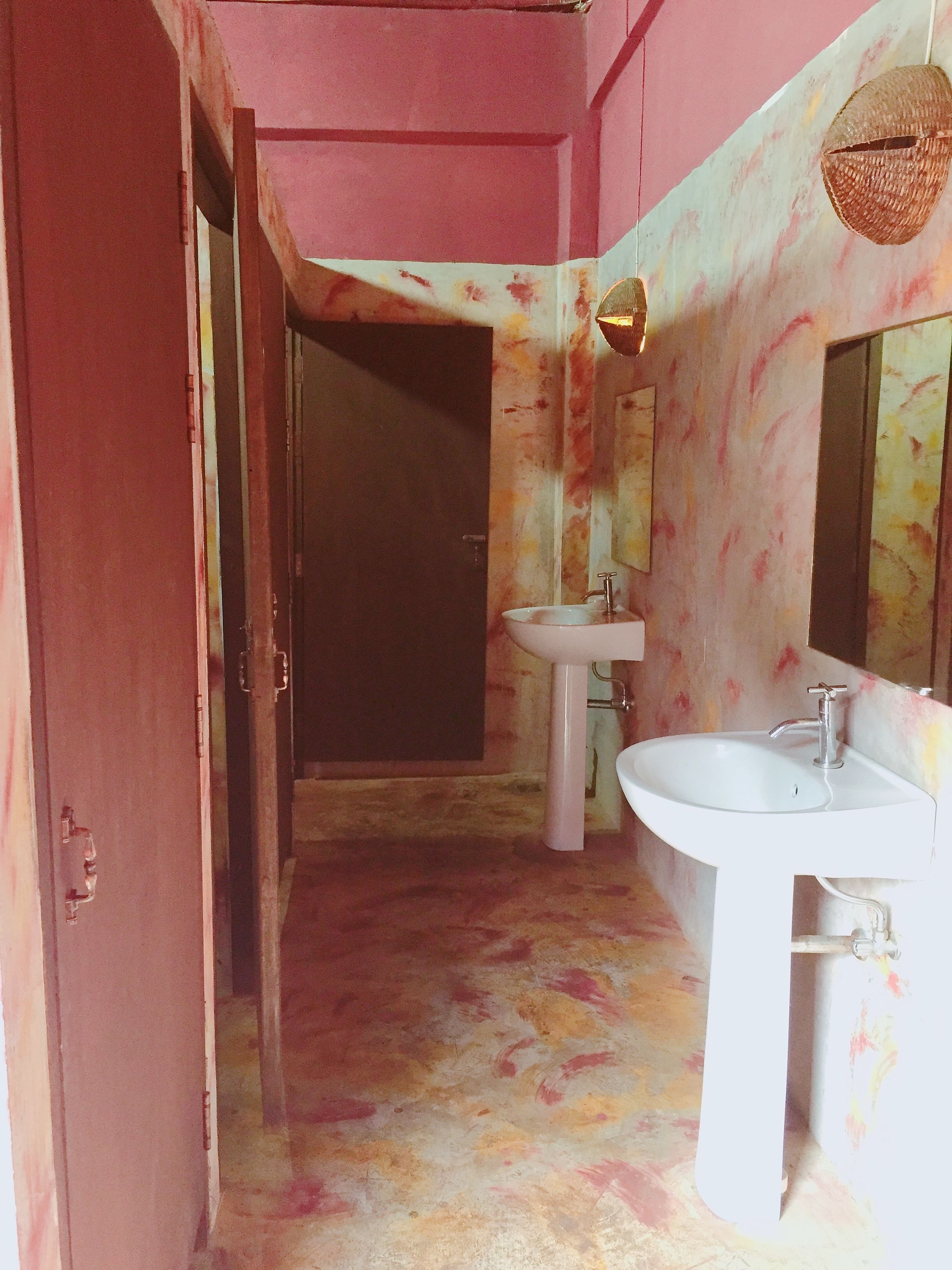 Un baño con una puerta rosa, un lavabo y un espejo.