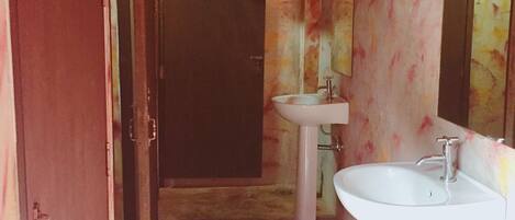 Un baño con una puerta rosa, un lavabo y un espejo.