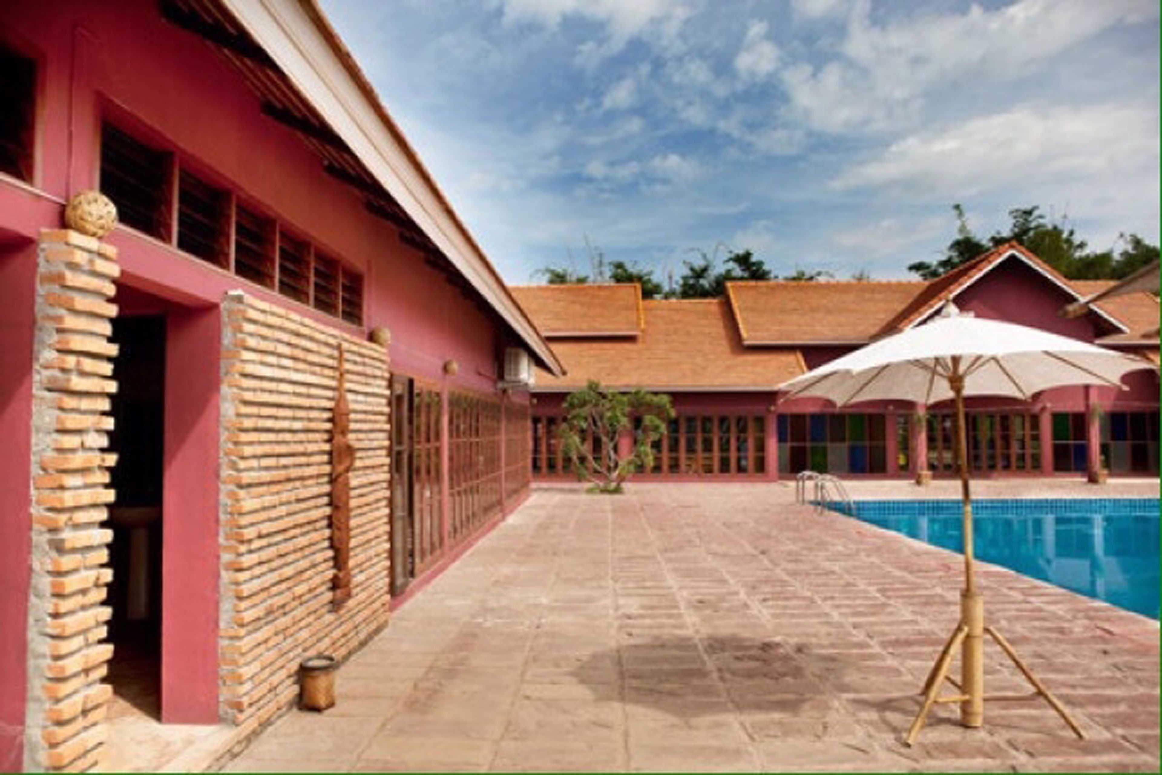 A pool area with a tiled floor, a brick wall, and a building with large windows.