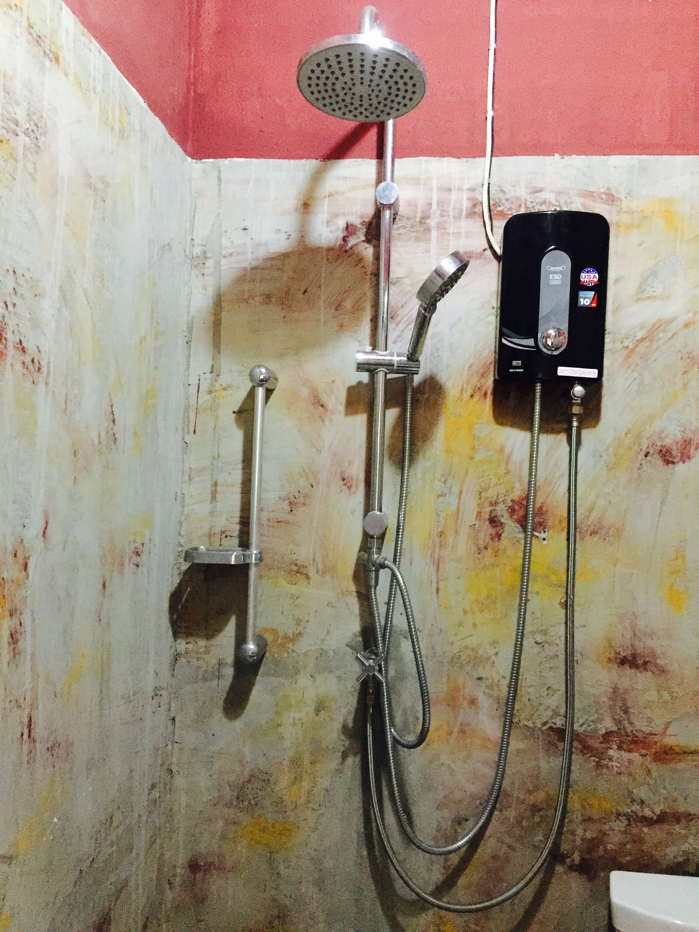 A shower area with a handheld showerhead, a wall-mounted showerhead, and a handheld shower hose.