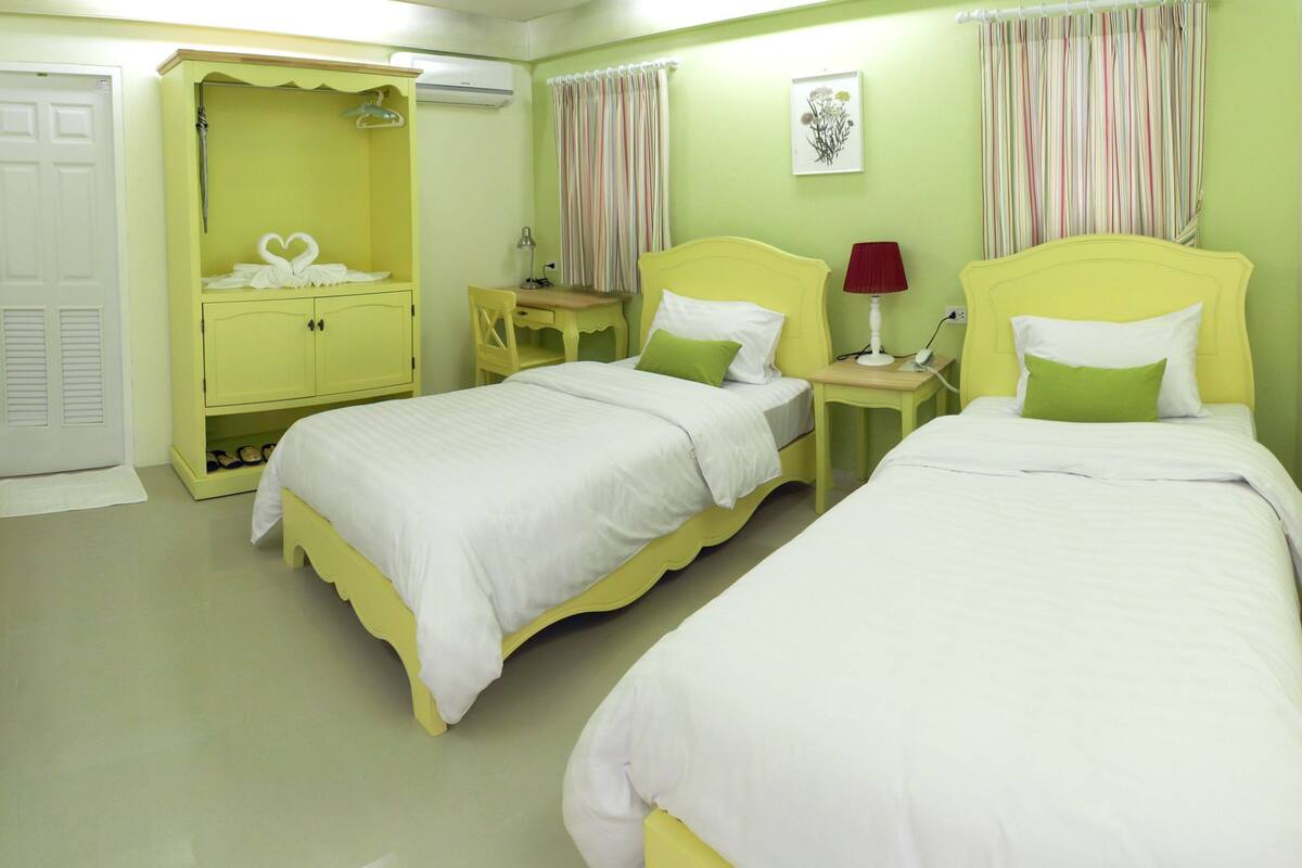 A room with two beds, a wardrobe, a desk, and a chair.