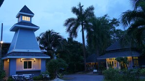 A resort with a prominent building featuring a peaked roof and a small tower with lights. - A Little Villa (Krabi)