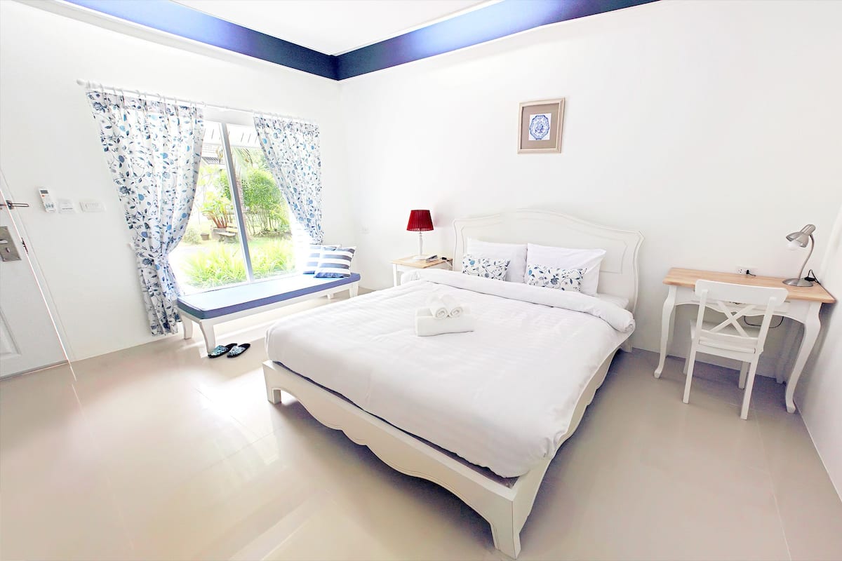 A neatly arranged bedroom with a bed, a desk, and a chair.