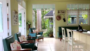 A room with green chairs, a white desk, and a view of greenery outside. - A Little Villa (Krabi)