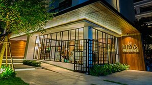 A modern building with a glass facade, a wooden entrance, and a sign that reads "UMA RESIDENCE." - UMA Residence (Bangkok)