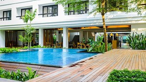 A modern hotel with a swimming pool, wooden deck, and lush greenery. - UMA Residence (Bangkok)