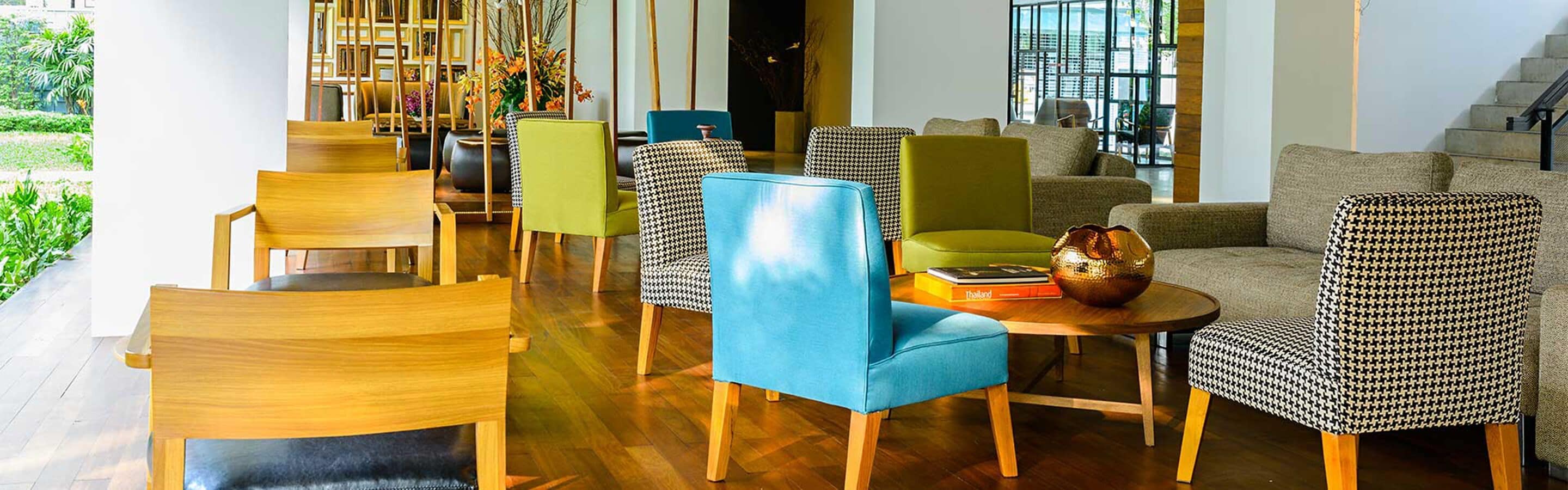 A modern lounge area with wooden and houndstooth patterned chairs, a blue sofa, and a round table with a decorative bowl.
