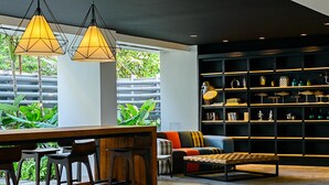 A modern interior with a bar area, seating, and a large bookshelf. - UMA Residence (Bangkok)